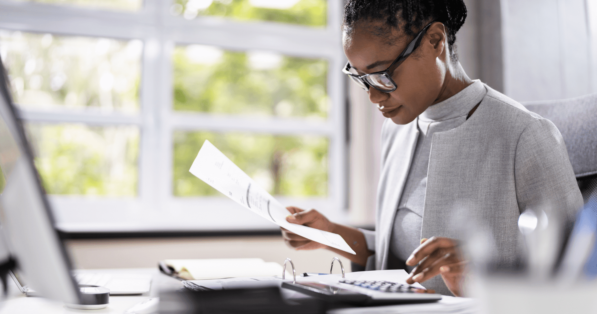 Project Control Lady In Glasses At A Computer With Papers And A Calculator